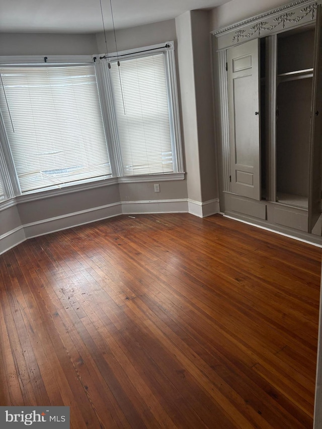 unfurnished bedroom featuring multiple windows and dark wood-type flooring