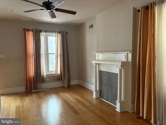 unfurnished living room with ceiling fan, a tiled fireplace, and light hardwood / wood-style flooring