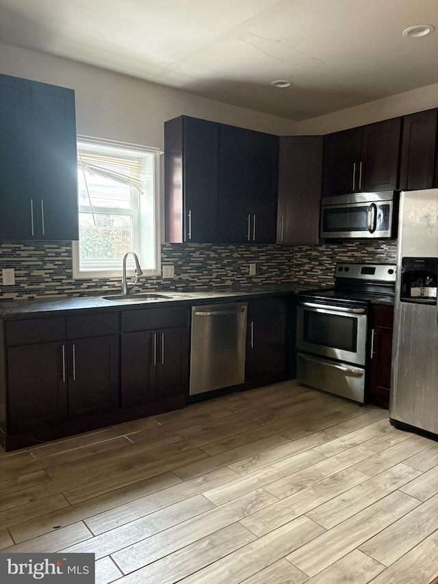 kitchen with dark brown cabinetry, sink, stainless steel appliances, and light hardwood / wood-style floors