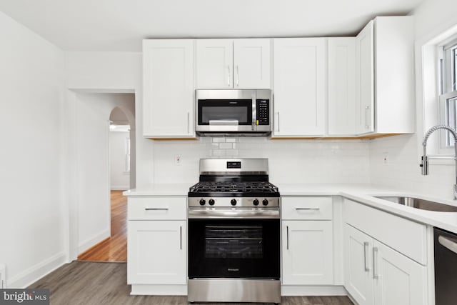 kitchen featuring white cabinets, sink, decorative backsplash, appliances with stainless steel finishes, and light hardwood / wood-style floors