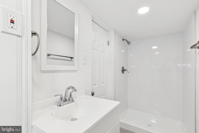 bathroom with a tile shower and vanity