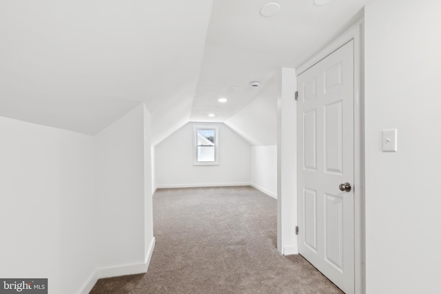 additional living space featuring light carpet and vaulted ceiling