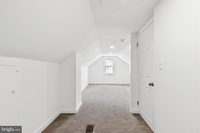 additional living space featuring light colored carpet and vaulted ceiling