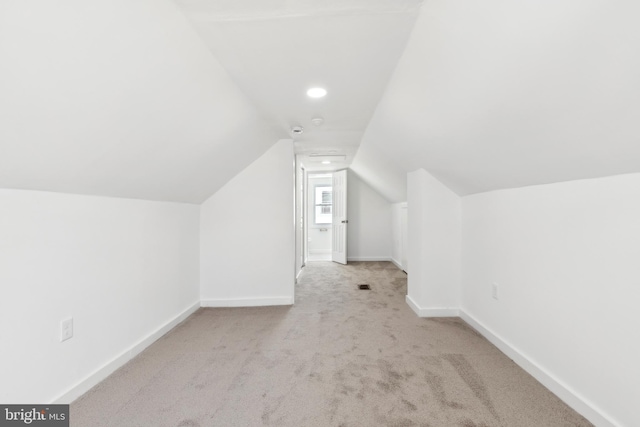 additional living space featuring light colored carpet and lofted ceiling