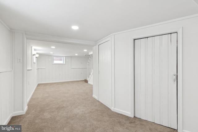 basement featuring light colored carpet and crown molding