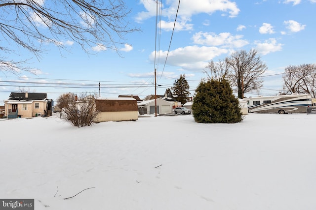 yard covered in snow with a garage and an outdoor structure