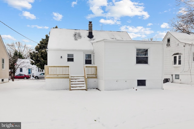 snow covered house featuring central AC unit