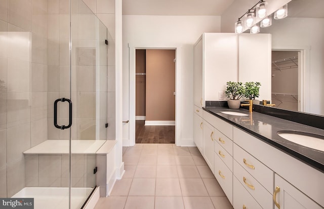 bathroom with tile patterned floors, a shower with door, and vanity