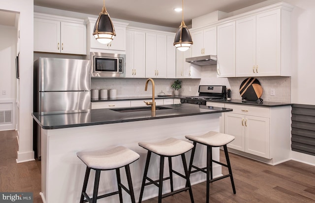 kitchen with hanging light fixtures, white cabinetry, a kitchen island with sink, and appliances with stainless steel finishes