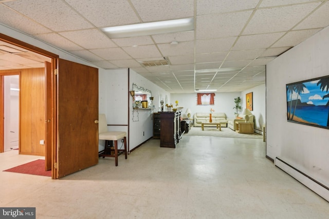 basement with a drop ceiling and a baseboard heating unit