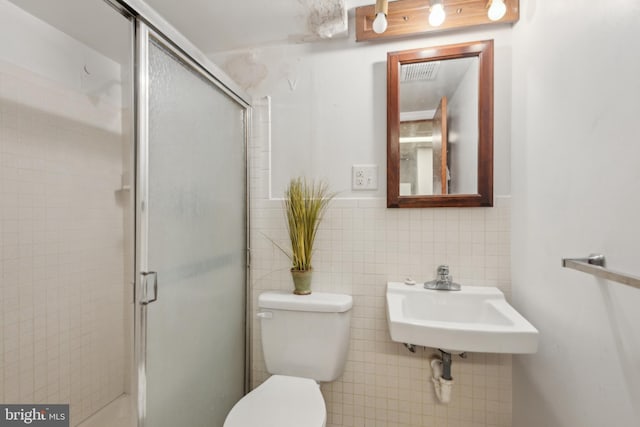 bathroom featuring an enclosed shower, toilet, tile walls, and sink