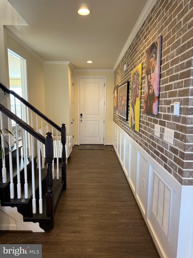 hall with dark hardwood / wood-style flooring, ornamental molding, and brick wall