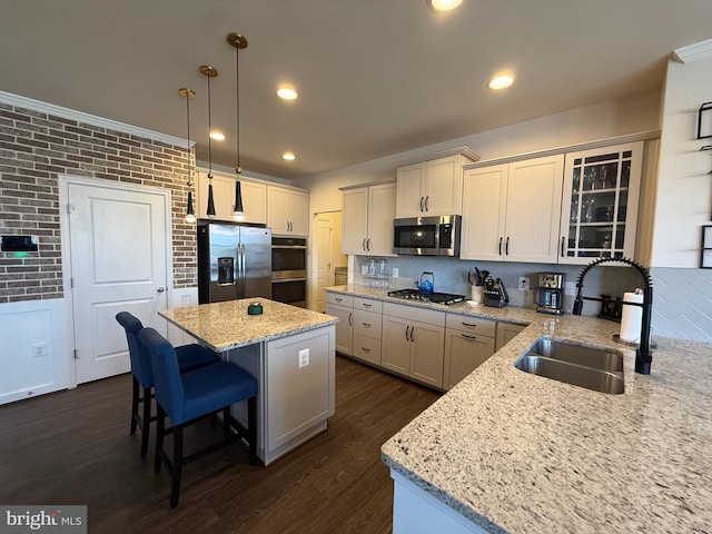 kitchen featuring light stone countertops, stainless steel appliances, sink, decorative light fixtures, and a center island