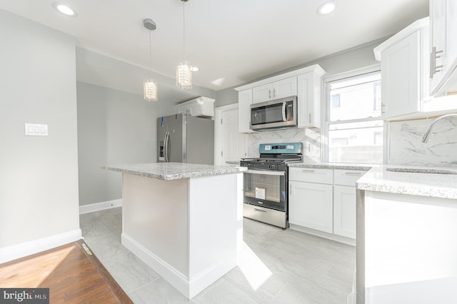 kitchen with appliances with stainless steel finishes, tasteful backsplash, sink, a center island, and white cabinetry