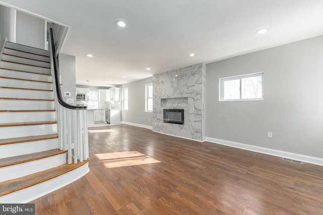 unfurnished living room with a large fireplace and dark wood-type flooring