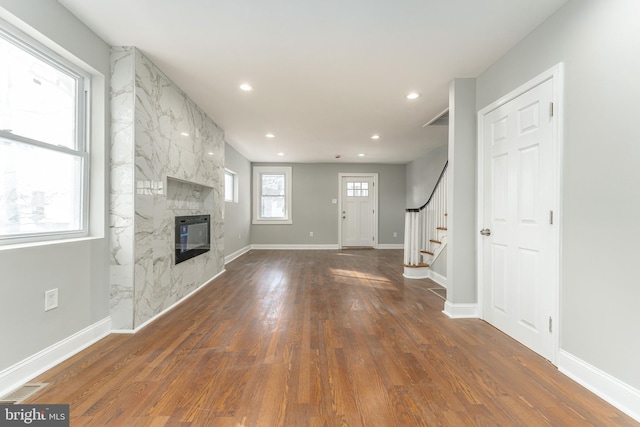 unfurnished living room featuring dark wood-type flooring and a premium fireplace