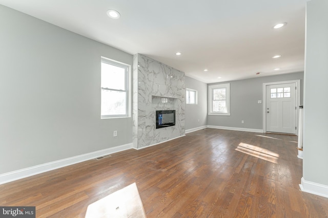 unfurnished living room with a premium fireplace and dark wood-type flooring