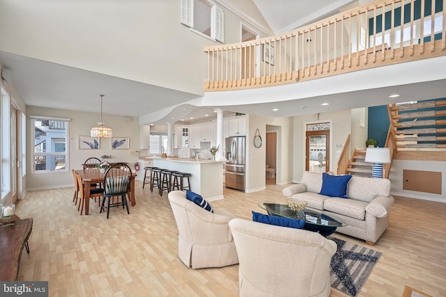 living room with light hardwood / wood-style floors, a high ceiling, sink, and a chandelier