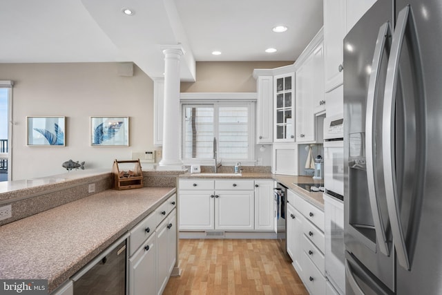 kitchen featuring sink, white cabinets, stainless steel fridge, and ornate columns