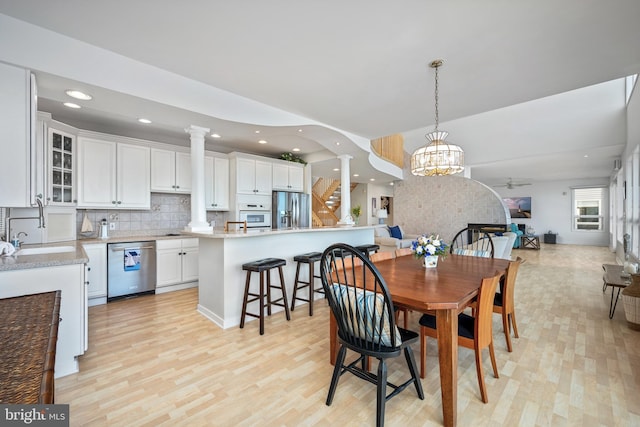 dining area featuring sink, a notable chandelier, and light wood-type flooring