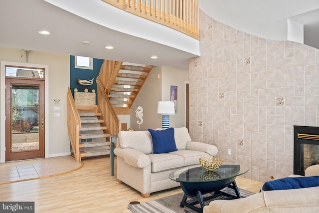 living room featuring tile walls, a tile fireplace, and light wood-type flooring