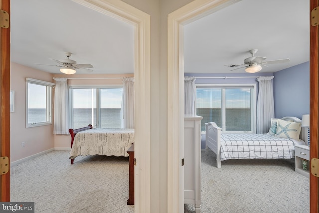 carpeted bedroom with ceiling fan and a water view