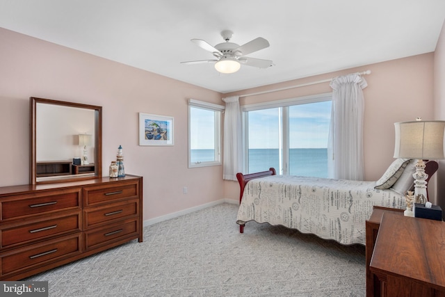 bedroom featuring ceiling fan, a water view, and light colored carpet