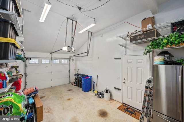 garage with a garage door opener and stainless steel refrigerator