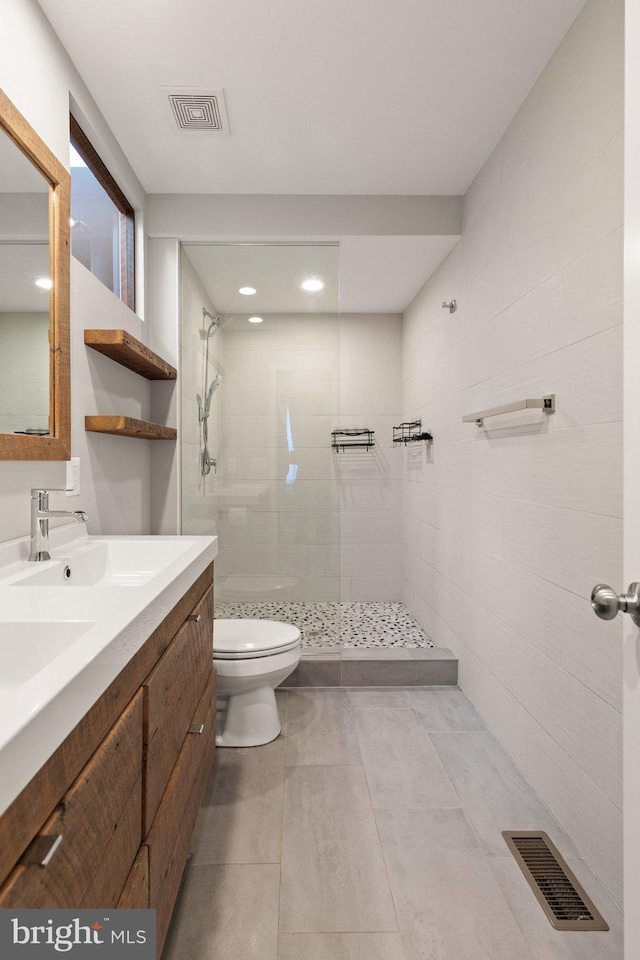 bathroom with toilet, vanity, and tiled shower