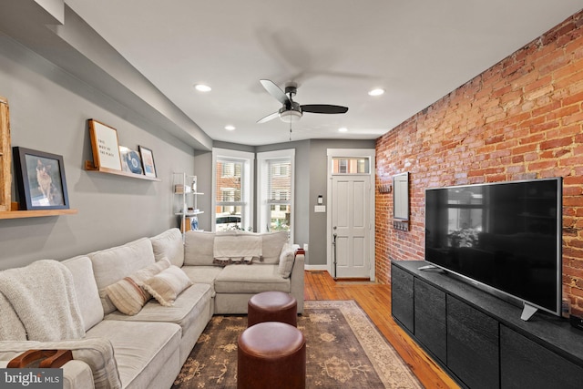 living room with ceiling fan, brick wall, and light wood-type flooring