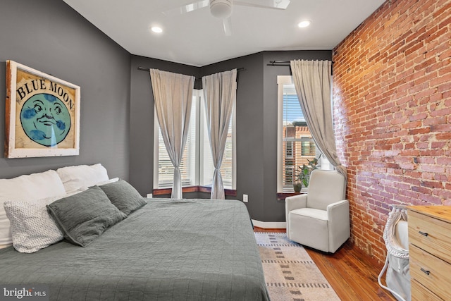 bedroom with ceiling fan, light hardwood / wood-style flooring, and brick wall