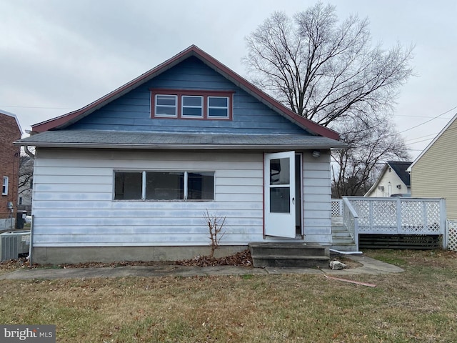 bungalow-style home featuring a front yard, a deck, and central air condition unit