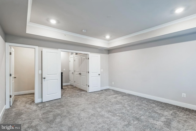 unfurnished bedroom featuring carpet floors, crown molding, a closet, and a raised ceiling