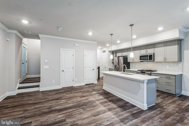 kitchen featuring an island with sink, gray cabinets, appliances with stainless steel finishes, backsplash, and pendant lighting