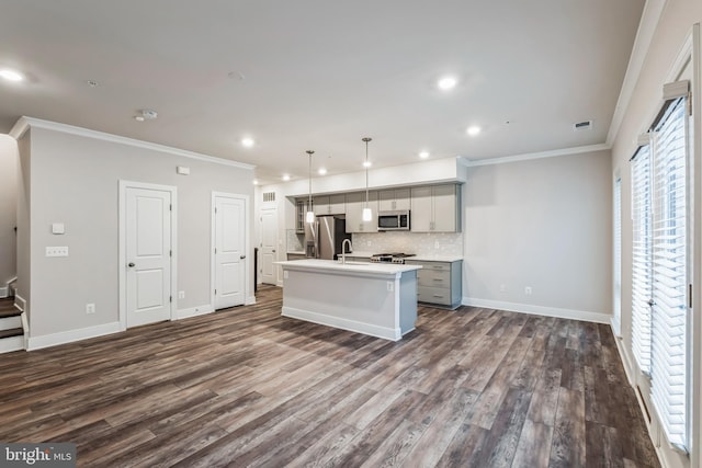 kitchen with an island with sink, gray cabinets, appliances with stainless steel finishes, dark hardwood / wood-style floors, and pendant lighting