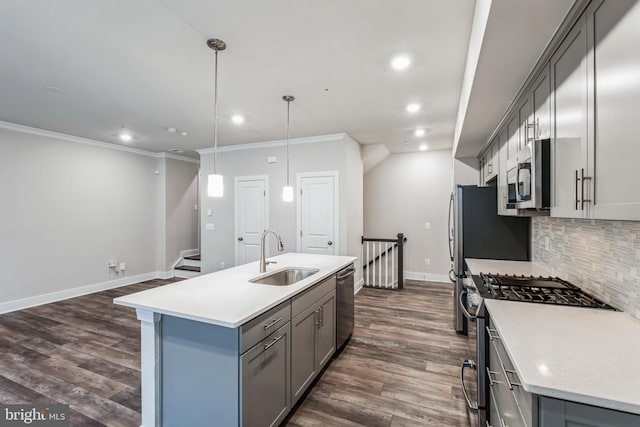 kitchen featuring stainless steel appliances, sink, hanging light fixtures, gray cabinets, and a center island with sink