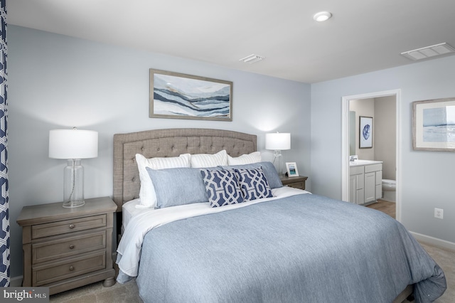 bedroom with ensuite bathroom and light colored carpet