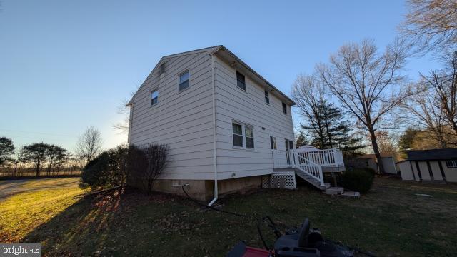 view of property exterior featuring a yard, a deck, and a storage shed