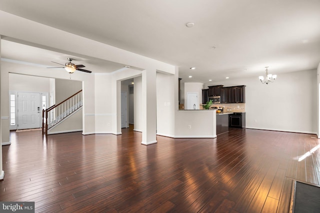 unfurnished living room with dark wood-type flooring and ceiling fan with notable chandelier