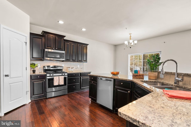 kitchen featuring appliances with stainless steel finishes, sink, backsplash, dark hardwood / wood-style flooring, and hanging light fixtures