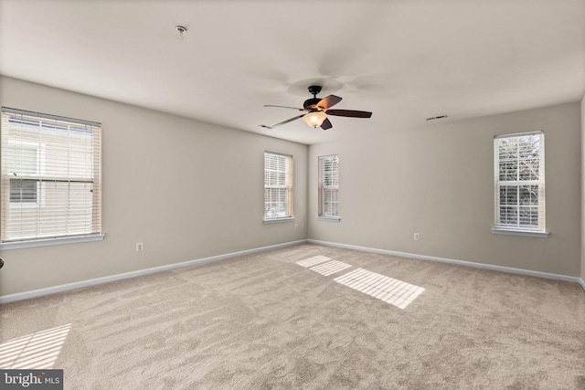 spare room with a healthy amount of sunlight, light colored carpet, and ceiling fan