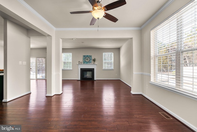 unfurnished living room with dark wood-type flooring, ornamental molding, and a healthy amount of sunlight