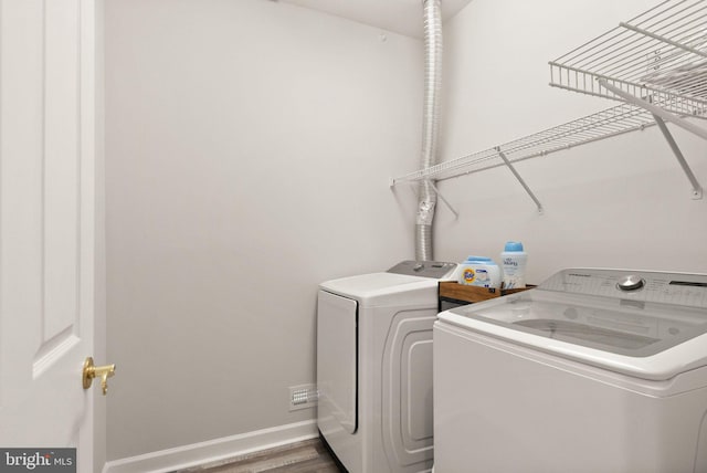 clothes washing area with washing machine and dryer and hardwood / wood-style flooring