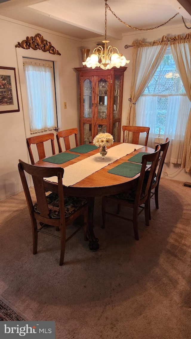 dining space featuring carpet flooring, ornamental molding, and a chandelier