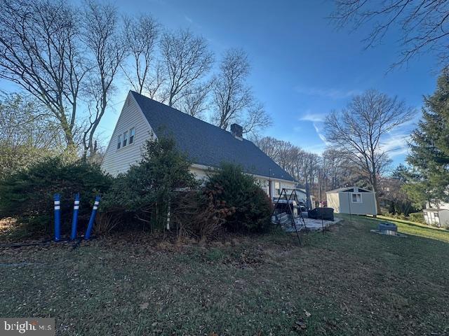 view of home's exterior with a storage unit and a yard