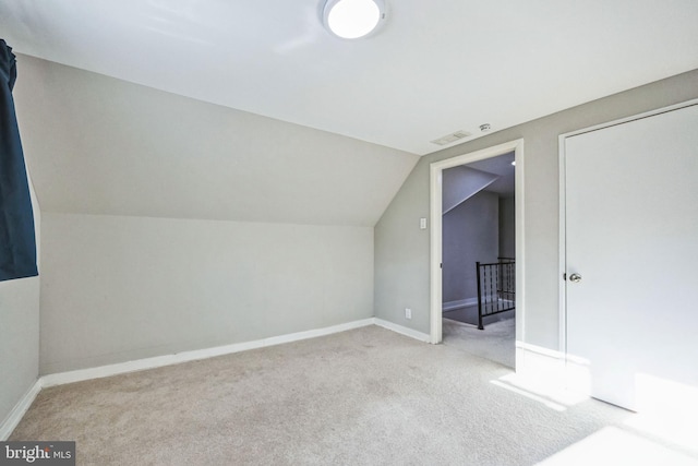 additional living space featuring light colored carpet and vaulted ceiling