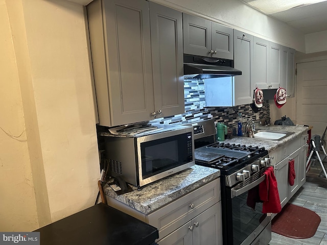 kitchen with sink, light hardwood / wood-style flooring, gray cabinets, tasteful backsplash, and stainless steel appliances