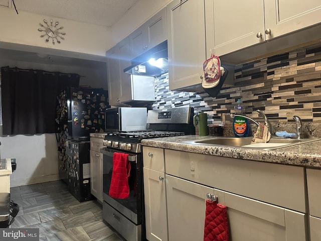 kitchen with gas stove, decorative backsplash, and sink