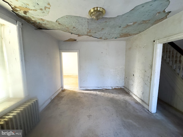 unfurnished room featuring radiator heating unit and concrete floors