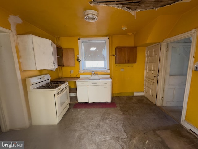 kitchen featuring concrete floors, white cabinetry, and white gas stove